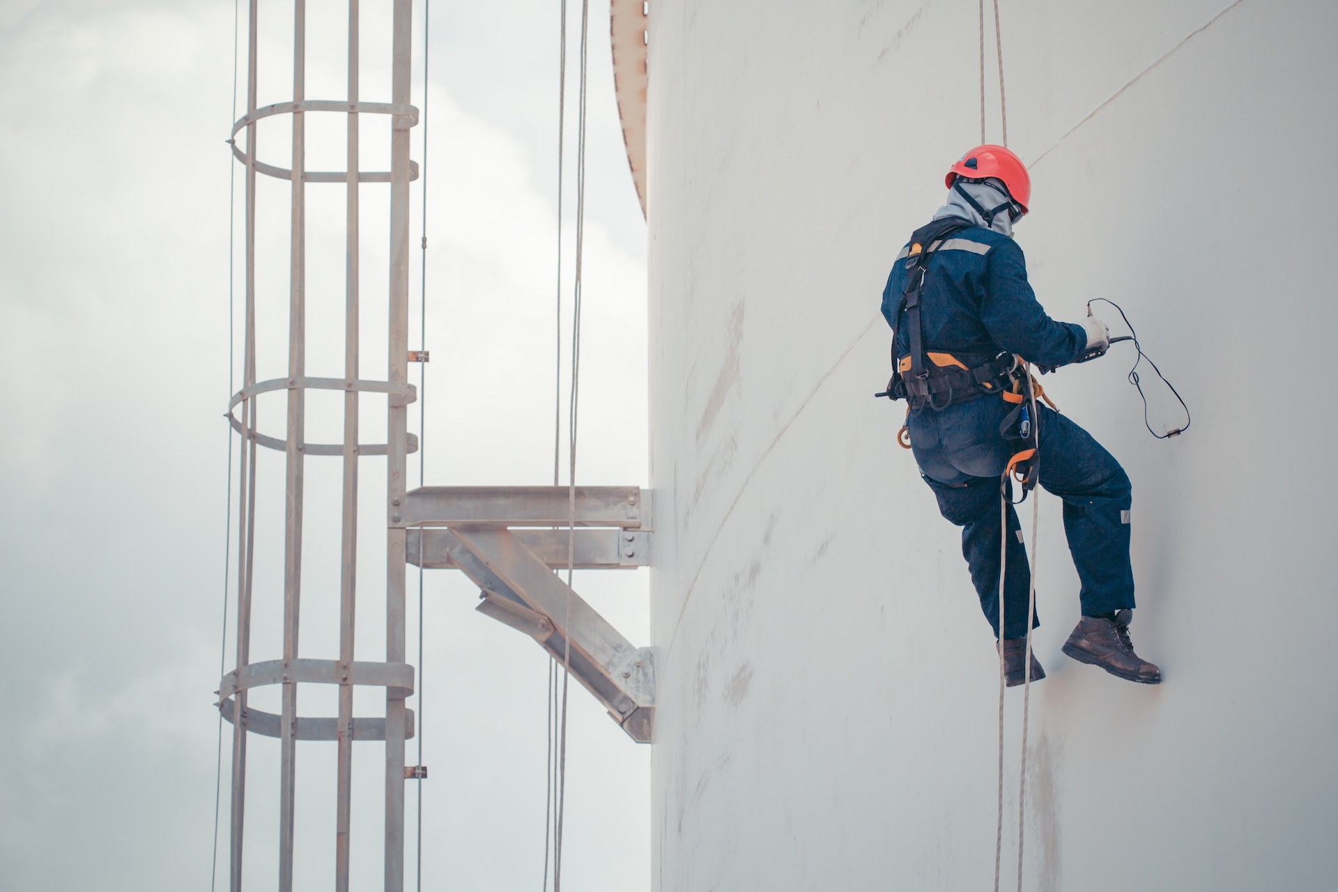 Male worker rope access inspection of thickness storage tank